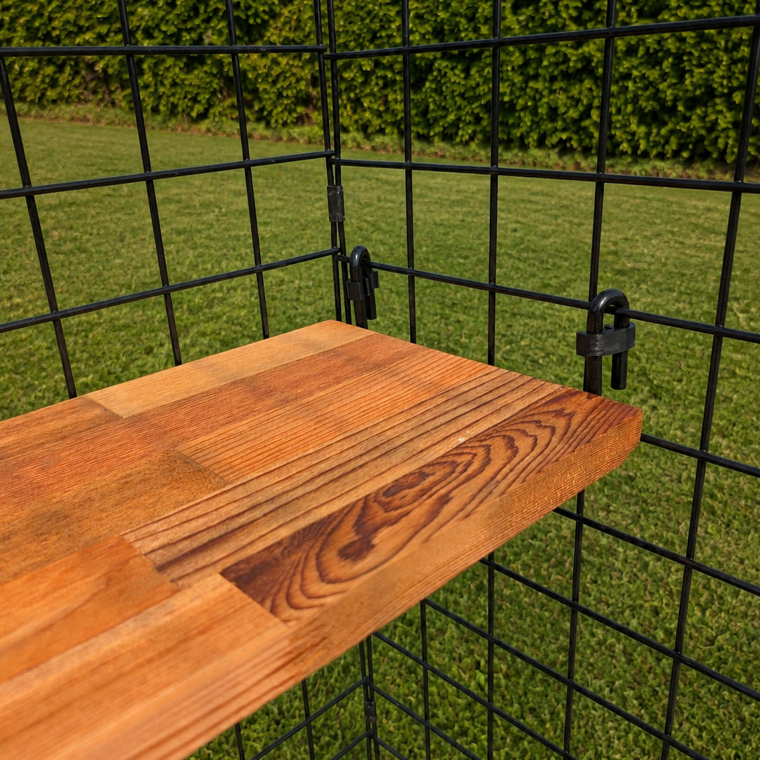 A Catio Shelves unit, featuring cedar planks securely mounted onto a black wire grid frame, is displayed outdoors with green grass and hedges in the background—demonstrating a stylish and sturdy wood shelving solution supported by robust shelf brackets.